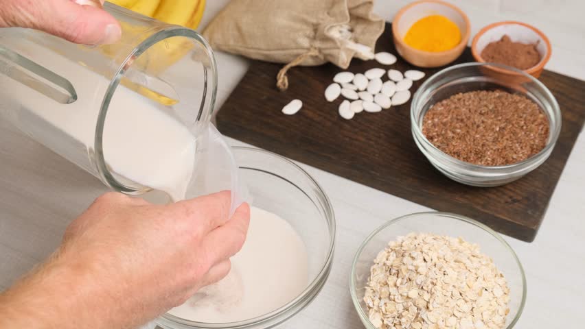 Filtering homemade oat milk using mesh straining bag. Vegan dairy-free milk alternative made from rolled oats. Plant-based base for smoothies. Vegetarian lifestyle and clean healthy habits.