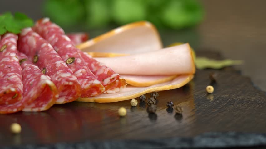 Camera movement on fresh slices cold cuts, sausage ham bacon jamon on cutting board. Meat pork beef. Food