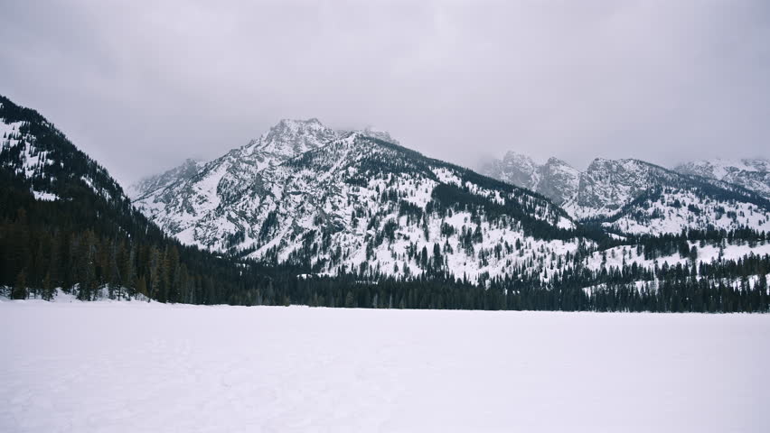 Frozen Lake with Snowy Mountains and Pine Forest