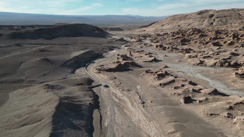 A Drone view of White car driving through the rugged, terrain of Death Valley in Atacama Desert, Chile