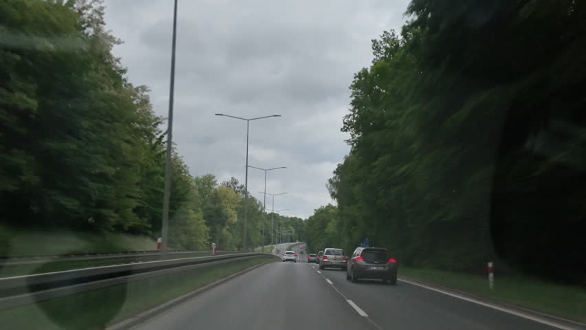 POV highway drive through green forest on a cloudy day. Watch calm traffic scenes, tree-lined roads and a peaceful travel atmosphere. Great for travel vlogs, relaxation, background visuals or