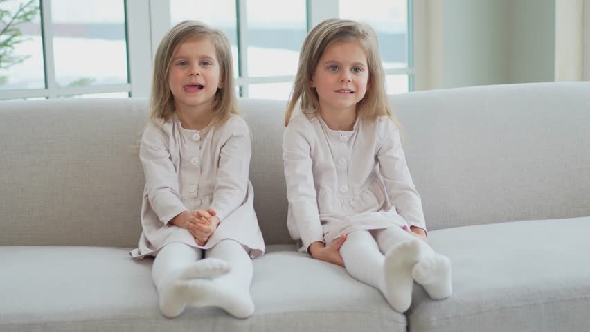 Happy family sisterly love. Two funny little twin sisters girls smiling playing together at home indoors. Happy children lifestyle. Identical twin girls. Girls friendship and youth
