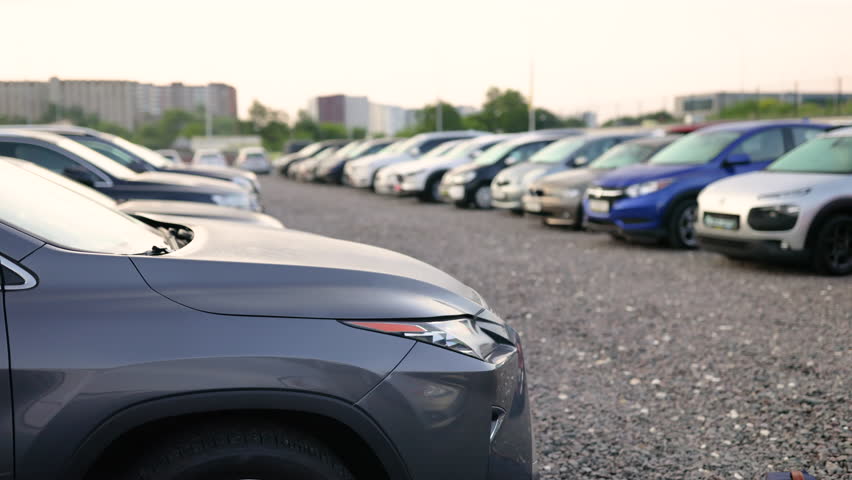A row of cars are parked outdoors, with a focus on the front of a gray luxury SUV. The image highlights the sleek design and modern aesthetic of the vehicles.