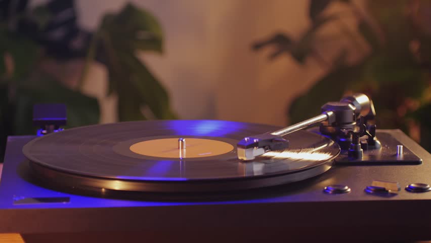 Retro Vinyl record player playing music, close-up macro shot of vintage LP disc old phonograph spinning. Retro music player at home.
