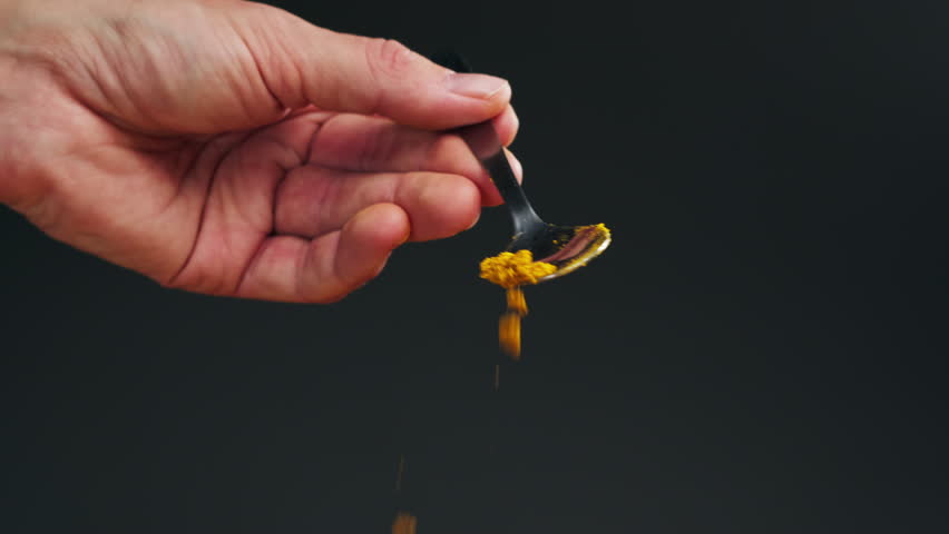 Spice turmeric powder on spoon close up. Sprinkle turmeric powder. Spice for food and drinks. Healthy