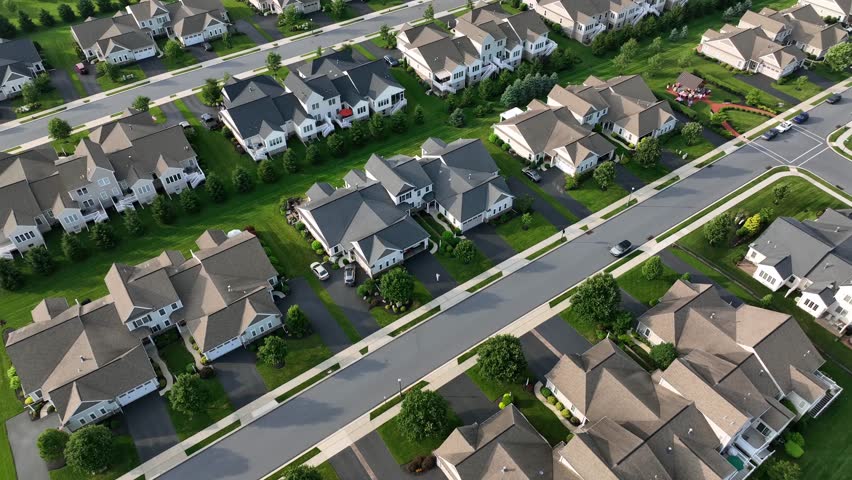 Exclusive and noble houses in wealthy suburb district of American town. Sunset time in summer. Aerial top down flyover. Large homes and villas in well-kept area of city. Quiet scene.