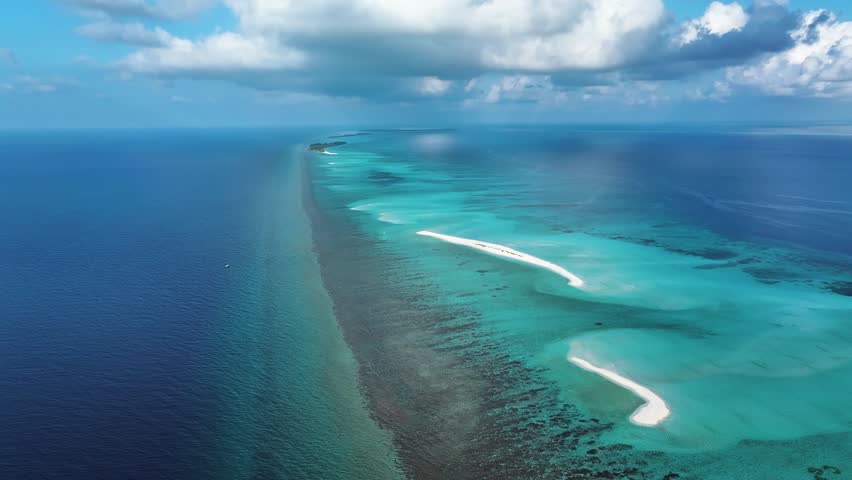 Aerial view of pristine white sandbanks cutting through the vibrant turquoise waters under a partly cloudy sky, Goidhoo, Baa Atoll, Maldives.
