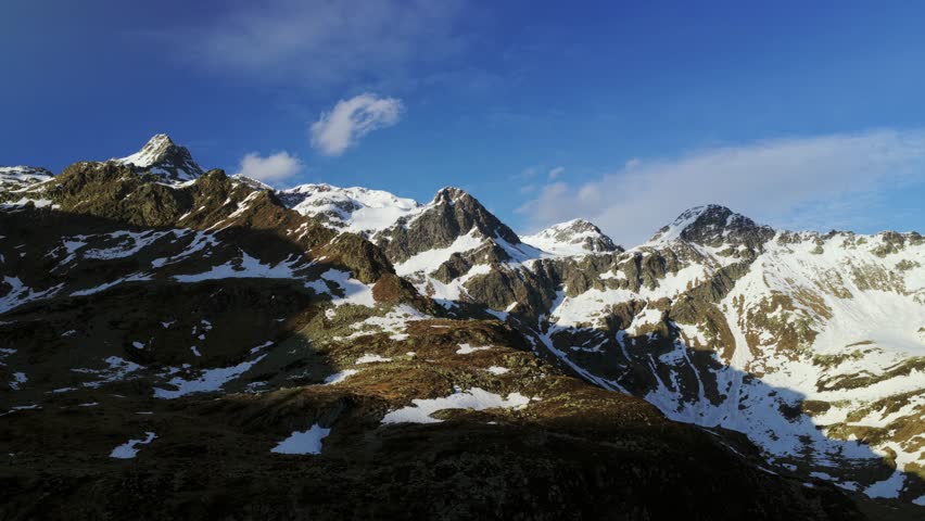 Majestic snow-capped Montespluga mountain range in Italian Alps. Aerial drone lateral view