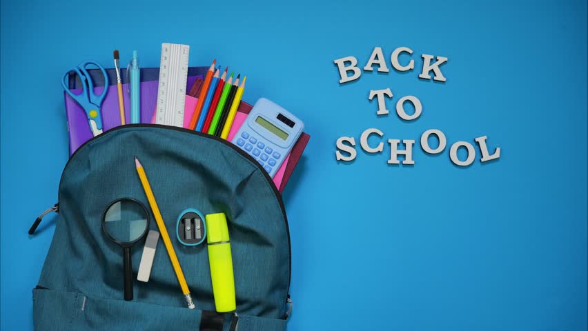 From the school bag appear colorful school supplies on blue background. Back to school concept . Place for inscription. Stop motion