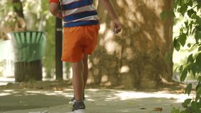 A young boy draws with chalk on a sunlit sidewalk, fully absorbed in his creative play. He is surrounded by lush greenery and large trees in a peaceful park in Simferopol, Crimea. - Powered by Shutterstock - Get 15% off with code: PIKWIZARD15