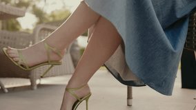 A close-up shot of a woman's feet in fashionable green high heel sandals, sitting outside in a casual setting. Emphasizes style, fashion, and outdoor relaxation. Relaxed Woman Sitting Outdoors - Powered by Shutterstock - Get 15% off with code: PIKWIZARD15