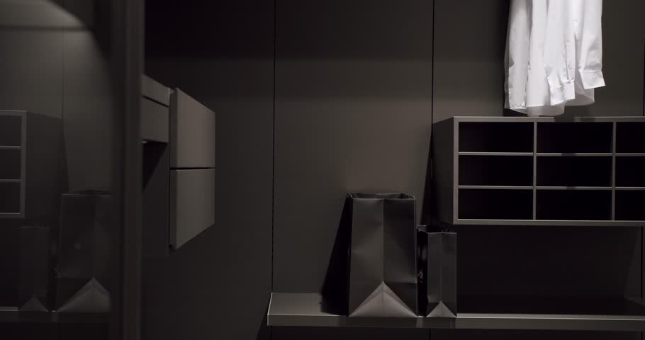 Black wardrobe with Sliding Black Doors. Luxury Bedroom With Walk In Closet. Dressing room with shirts. Elegant Wooden Built Walk In Closet Decoration. Luxury Dressing Room. Modern Sliding Doors.