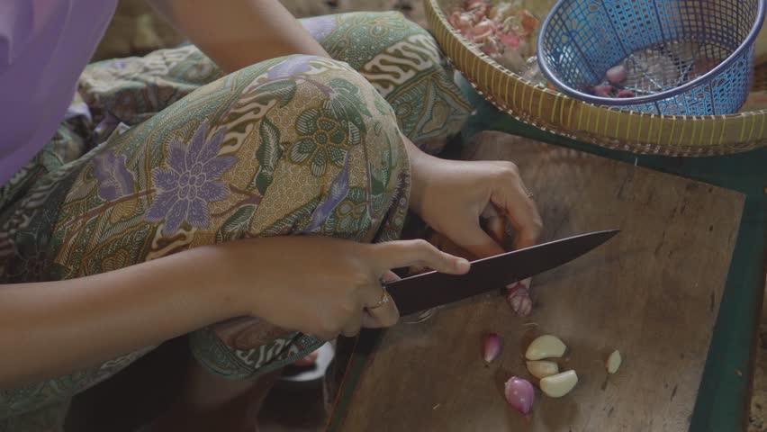 Woman cutting garlic and red onion for cooking