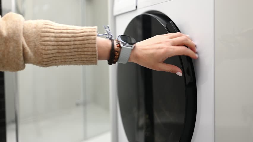 Woman Puts Clothes In The Washing Machine, Hands Hold A White Towel