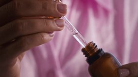 Hand of young unrecognizable woman holding pipette with transparent serum dropping into bottle with cosmetic product before applying it on her face during self care ritual - Powered by Shutterstock - Get 15% off with code: PIKWIZARD15