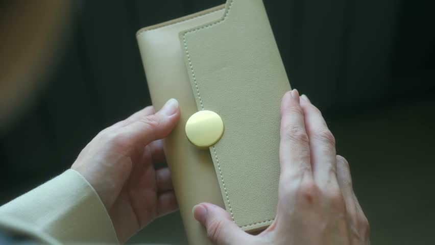 Female hands revealing empty beige wallet, signaling financial struggle and economic hardship faced by professional woman experiencing monetary challenges. Woman opening empty beige wallet
