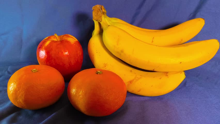 Assorted fresh ripe vibrant fruits of banana, oranges, apple on a dark background. Bright colorful display. Refreshing healthy organic natural nutrition. Copy space. Active diet lifestyle ingredients.