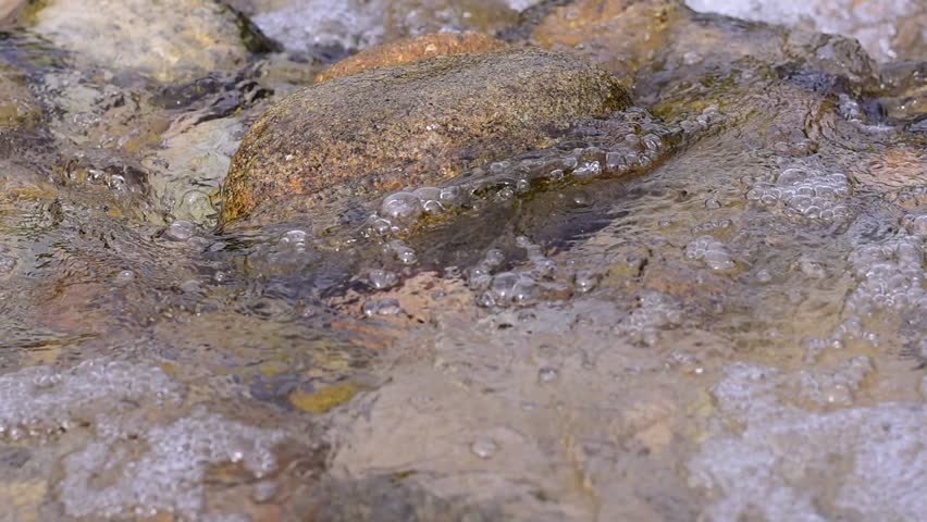 pebble stones on the sea beach, the rolling waves of the sea with foam, Dam water flow, Surface flow,Dam handmade with stones A small river