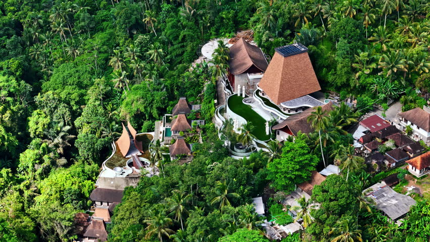 Lush jungle surrounds luxury resort villas in tropical Ubud, Bali from above