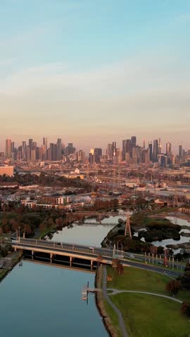 Aerial Melbourne city skyline at dawn, reflecting pink and orange on the buildings and Maribyrnong River, showcases urban beauty