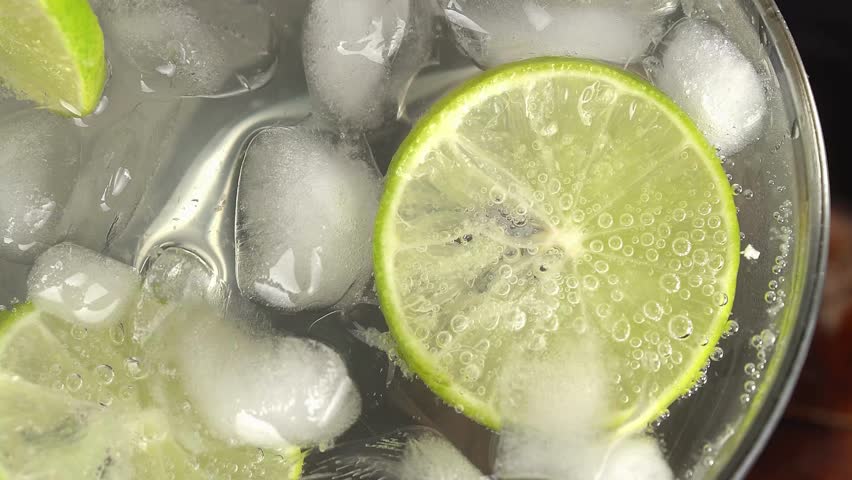 Close-up of lime slices in a glass with ice. A close-up of a refreshing beverage shows fizzy bubbles rising around ice cubes and fresh lime slices in a glass, evoking summer and coolness. Macro shot. - Powered by Shutterstock - Get 15% off with code: PIKWIZARD15