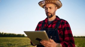 Portrait of handsome young adult farmer in field, innovation in agribusiness. Male farm worker using tablet for planning future harvest and counting profits, agronomy and economy, medium shot outdoors - Powered by Shutterstock - Get 15% off with code: PIKWIZARD15