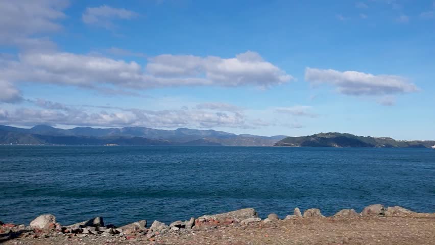 Moving train window view of Wellington harbour and ocean in capital city of Wellington, New Zealand Aotearoa