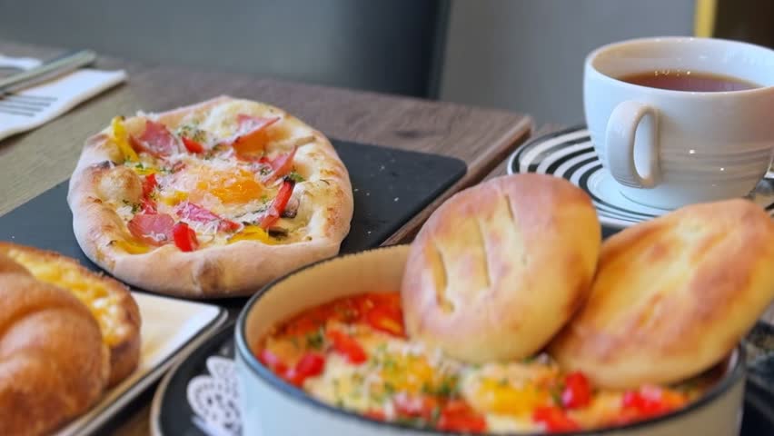 Delicious brunch with shakshuka, warm bread, cheesy flatbread, and tea—ideal for food, cafe, breakfast, lifestyle, or hospitality-themed visuals.