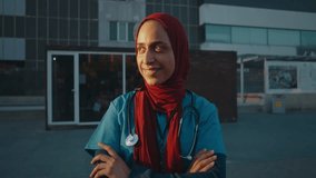 Professional muslim female doctor wearing hijab, confidently standing outside hospital, smiling with crossed arms while representing healthcare diversity and expertise - Powered by Shutterstock - Get 15% off with code: PIKWIZARD15