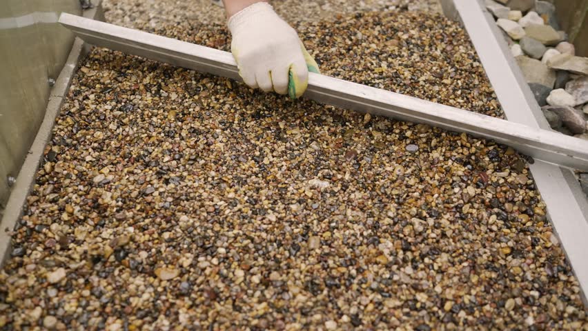 Construction worker leveling gravel with a rake