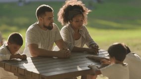 Happy family enjoying time together at a picnic table in a sunny park - Powered by Shutterstock - Get 15% off with code: PIKWIZARD15