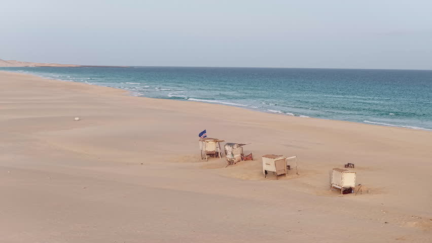 Praia de Chaves ( Chaves beach),Ocean,sandy dune and wooden shops on the beach with the Cape Verdean flag flying.Boa Vista island situated in the Atlantic Ocean.Cape Verde, Africa.