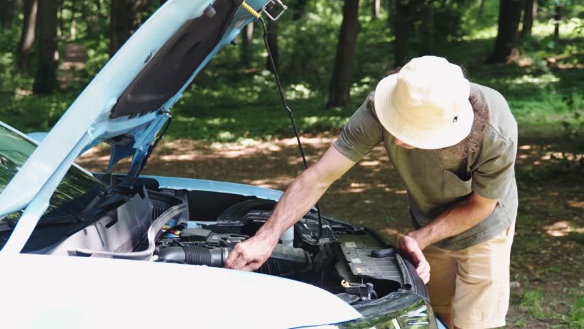 A young male traveler is trying to detect a breakdown in his car during a trip out of town
