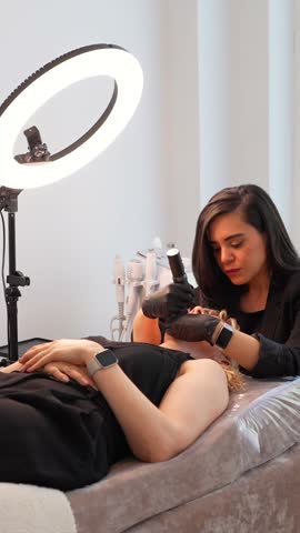 Professional beautician performing advanced facial treatment using specialized equipment, providing personalized skincare service with dermatological precision in modern wellness environment