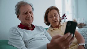 Close-up of senior couple holding and looking at a smartphone, engaged in a video call with family members, their hands and faces softly blurred, sharing a moment of connection and technology use - Powered by Shutterstock - Get 15% off with code: PIKWIZARD15