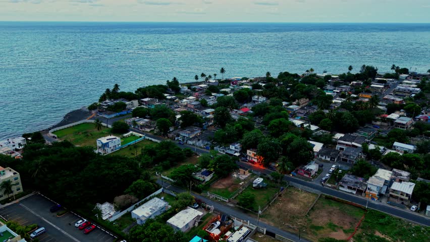 Aerial: Loiza neighborhood with Atlantic Ocean during the day in Puerto Rico, USA, orbit drone shot