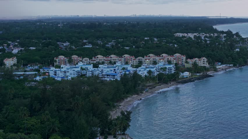 Aerial: Loiza cityscape with sand beach, Atlantic Ocean at sunset in Puerto Rico, USA, establishing drone shot