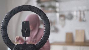 Muslim woman vlogger live streaming cooking online in kitchen look at camera with vegetables, content creator culinary class at home studio, halal food influencer cooking live, video for social media - Powered by Shutterstock - Get 15% off with code: PIKWIZARD15