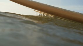 Slow motion extreme close-up of water trickling along the underside of a surfboard partially submerged in the sea. The camera follows the flowing detail. Shot in Domburg, Netherlands. - Powered by Shutterstock - Get 15% off with code: PIKWIZARD15