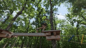 Child climbing in an adventure park among trees, wearing harness and helmet for safety, enjoying an outdoor challenge and active recreation - Powered by Shutterstock - Get 15% off with code: PIKWIZARD15