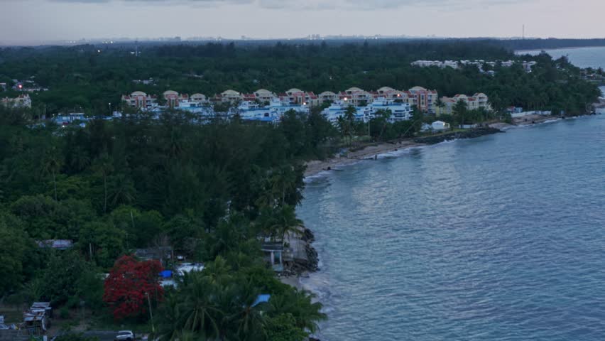 Crane up drone shot of Loiza cityscape with sand beach, Atlantic Ocean at sunset in Puerto Rico, USA