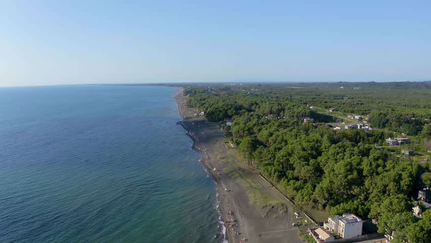 Drone view sea, beach and forest. Black Sea Coastline. Drone fly over beach near Black sea in Georgia. Touristic beach. View black sea coastline, with  green pine trees. 