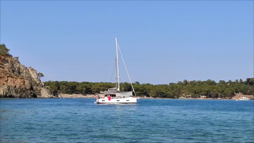 A white pleasure yacht in the blue Mediterranean sea against the backdrop of a picturesque forest place