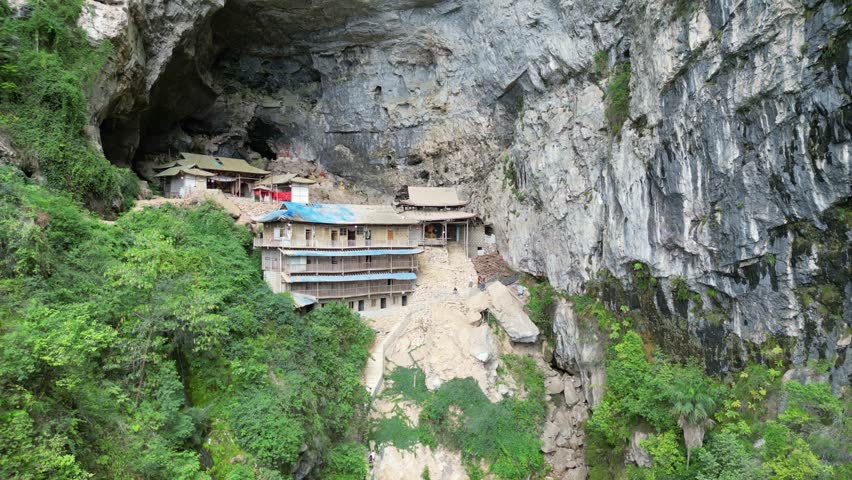 A dangerous wooden house built on top of a giant rock.