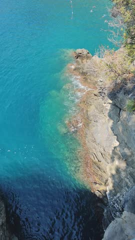 Azure water of the sea in summer. Rocky shore. Surf wave. People swimming. Holliday nature. Ocean beach top view