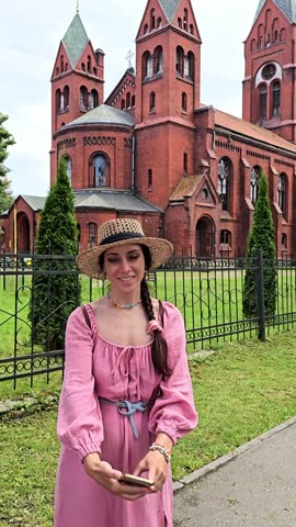 woman in pink dress and hat taking photo of herself against medieval building, girl taking selfie against building, travel around europe