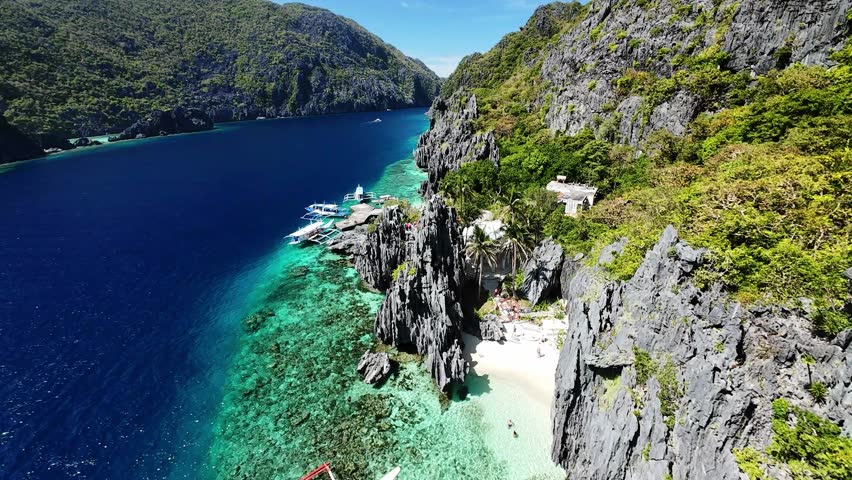 Tropical beach with boats and cliffs in El Nido, Palawan seen from drone perspective