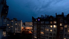 Time-lapse of a summer thunderstorm over residential buildings at night. Visible lightning flashes, dramatic clouds, and illuminated windows create a moody urban scene - Powered by Shutterstock - Get 15% off with code: PIKWIZARD15