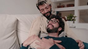 Two men, a gay couple, relax on the couch at home, enjoying each other's company. They look happy and in love. - Powered by Shutterstock - Get 15% off with code: PIKWIZARD15