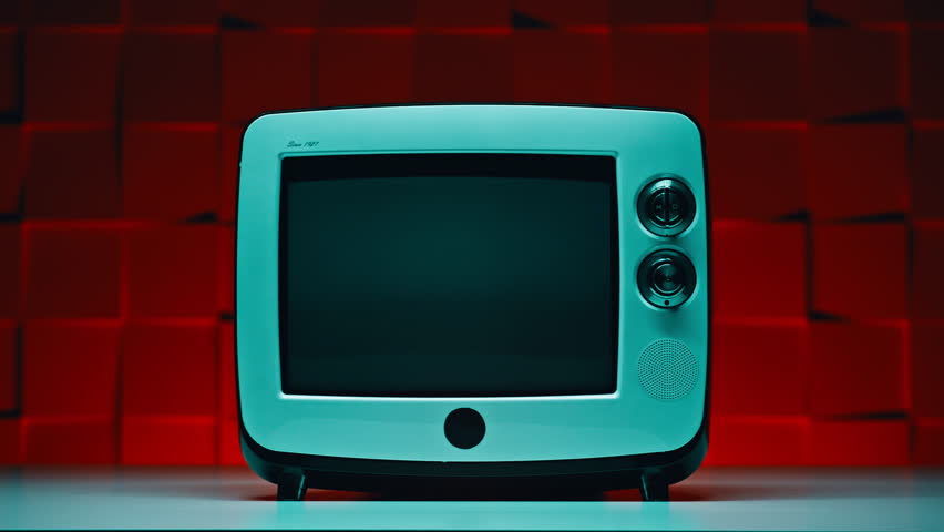 Closeup small retro TV standing at table on red textured background. Elegant vintage television device turned off placed in dark apartment room. Classic broadcasting device with black monitor indoors.